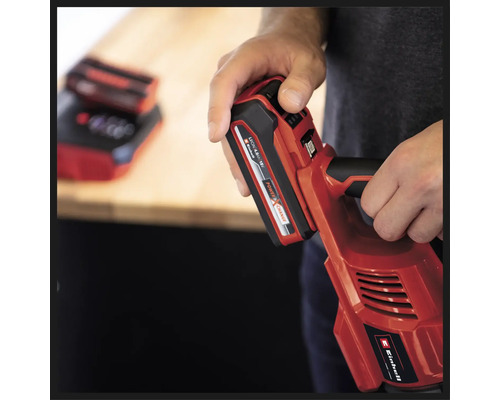 O persoană ține o unealtă roșie cu acumulator Einhell cu o baterie introdusă.