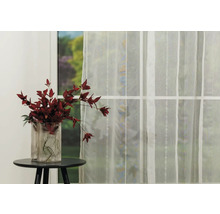 Cortină decorativă în fața unei ferestre, lângă care se află o vază cu flori pe o masă