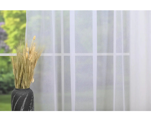 Cereale decorative în vază în fața unei ferestre cu o perdea albă transparentă