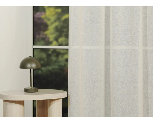 Scenă decorativă cu o măsuță laterală, o lampă și o perdea în fața unei ferestre.