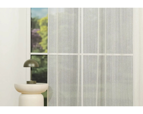 Fereastră cu perdea transparentă și lampă de masă