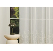 Perdea decorativă, transparentă, cu motiv floral în fața unei ferestre și a unei lămpi.