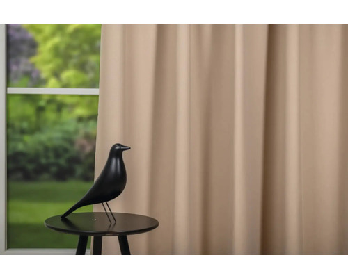 Statuie decorativă de pasăre pe o măsuță în fața unei ferestre cu perdea