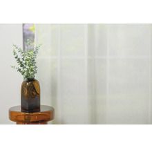 Crenguțe decorative verzi într-o vază de sticlă maro pe o măsuță laterală în fața unei ferestre