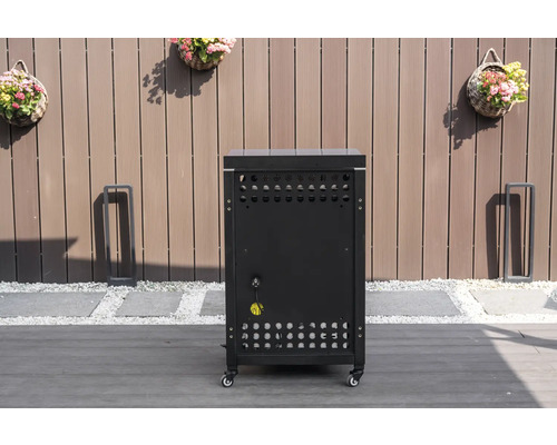 Dulap mobil de bază pentru bucătărie de exterior negru cu fante de ventilație și conexiune electrică pe o terasă în fața unui gard de lemn.