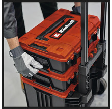 Cutii pentru scule sistem Einhell E-Case stivuite pe un cărucior, ținute de o mână cu mănușă de protecție.