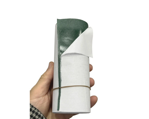 Bandă adezivă pentru îmbinare gazon artificial, rolă cu hârtia de protecție parțial dezlipită ținută în mână.