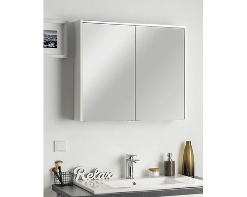 Dulap cu oglindă cu două uși într-o baie modernă, deasupra unei chiuvete cu baterie și decorațiuni.