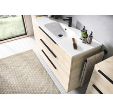 Mască pentru chiuvetă modernă din lemn deschis cu trei sertare, mânere negre, lavoar din ceramică albă și baterie neagră în baie.