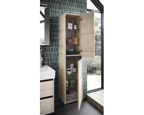 Dulap înalt de baie suspendat cu aspect de lemn deschis, două uși deschise, polițe de sticlă și accesorii de baie lângă un mobilier pentru lavoar.