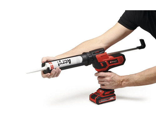 Pistol pentru cartușe cu acumulator Einhell cu un tub de acril introdus, ținut în mâna unui utilizator.