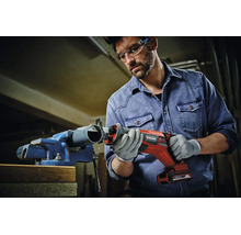 Un meseriaș utilizează un ferăstrău sabie cu acumulator Einhell pentru a tăia o țeavă din plastic fixată într-o menghină.