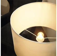 Lampadar modern cu abajur cilindric din material textil și sursă de lumină integrată pentru iluminarea luminoasă a încăperii.