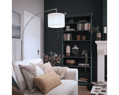 Lampă cu arc modernă cu abajur din material textil lângă o canapea într-un living confortabil cu rafturi închise și șemineu.