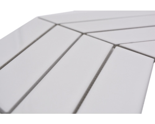 Prim-plan cu plăci ceramice albe, dreptunghiulare, dispuse în model herringbone.