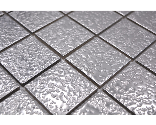 Prim-plan cu plăci de mozaic pătrate, argintii, cu o suprafață neuniformă.
