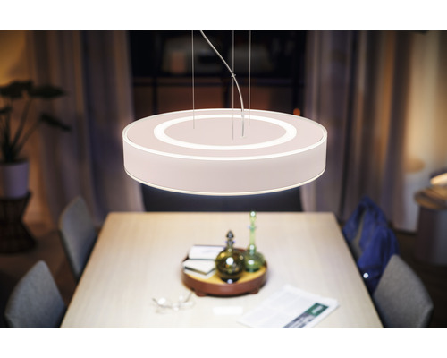 Abajur rotund iluminat din material textil deasupra unei mese de sufragerie.