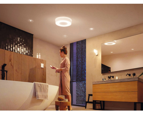 Baie modernă cu corpuri de iluminat de tavan, cadă și chiuvetă