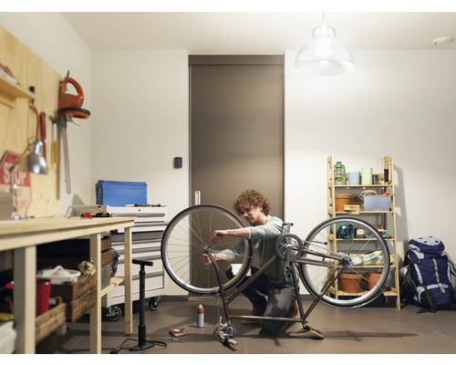 Bărbat reparând o bicicletă într-un atelier cu banc de lucru și raft