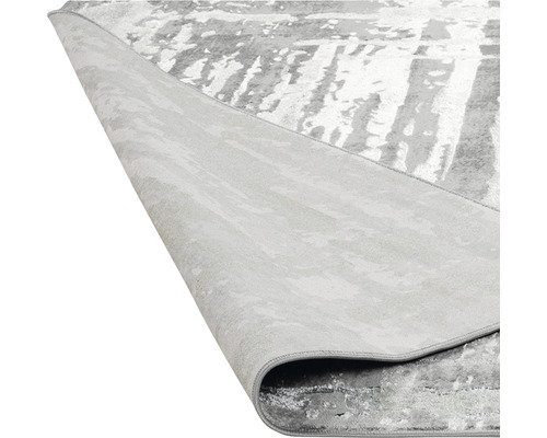 Imagine detaliată a unui covor gri cu model abstract, pliat pentru a arăta partea din spate.