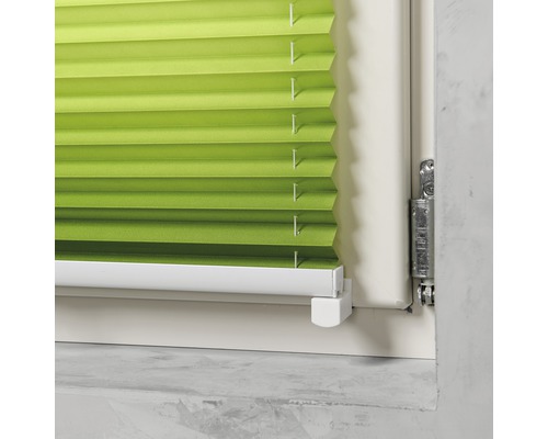 Prim-plan cu un jaluzele plisate verzi într-un toc de fereastră.