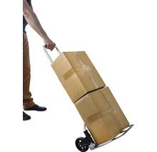 O persoană transportă două cutii de carton cu un cărucior.