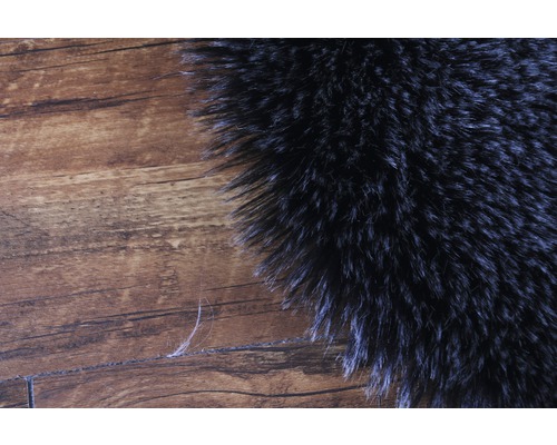 Prim-plan cu o parte a unui covor cu fibre lungi pe podea de lemn