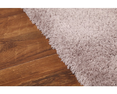 Imagine detaliată a unui covor cu fibre lungi pe o podea din lemn