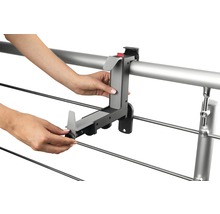 O persoană montează un suport pentru jardiniere pe o balustradă.