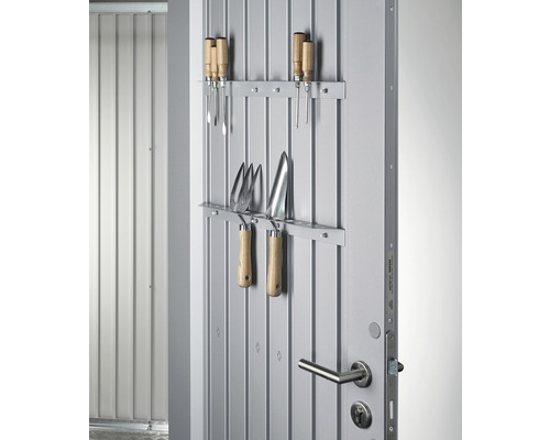 Unelte de grădinărit atârnate pe o ușă metalică pentru depozitare.