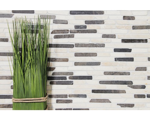 Plantă artificială decorativă în fața unui perete cu aspect de piatră