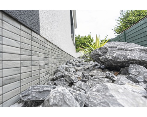 Perete de casă cu placare soclu și pietre în grădină