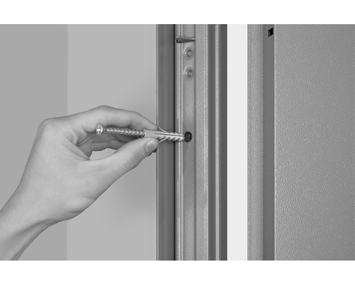 Mână introduce diblu cu șurub într-o gaură