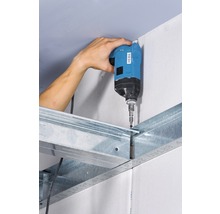 Un artizan fixează o placă de gips-carton pe o substructură metalică cu o șurubelniță cu acumulator.