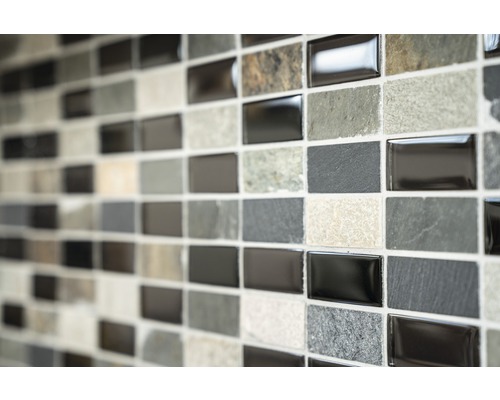 Perete de faianță mozaic cu plăci dreptunghiulare în diferite nuanțe de gri și texturi