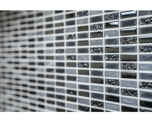 Prim-plan cu un perete cu plăci de mozaic în diferite nuanțe de gri și texturi.