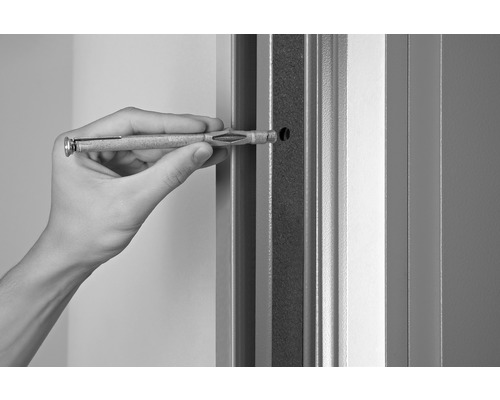 O persoană introduce un diblu pentru gips-carton într-un perete.