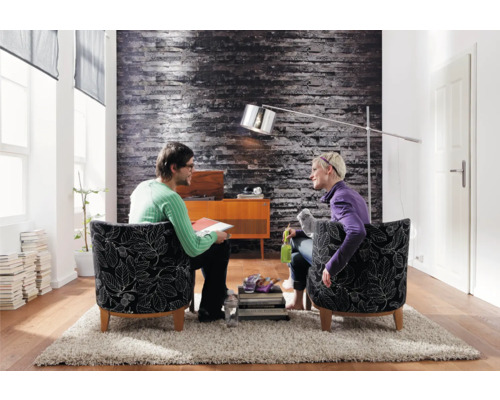 Living cu două persoane în fotolii, lampă de podea și decorațiuni pe un covor