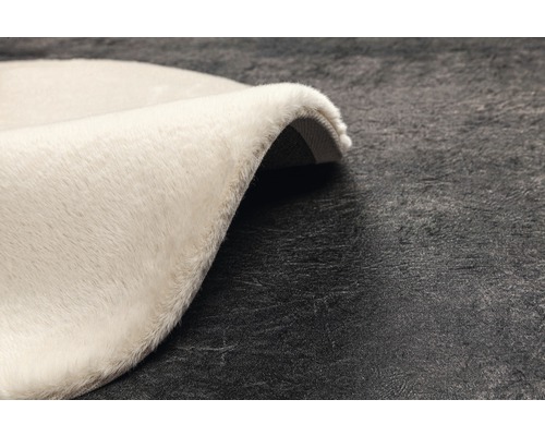 Prim-plan cu un covor rotund, de culoare deschisă, cu fibre lungi
