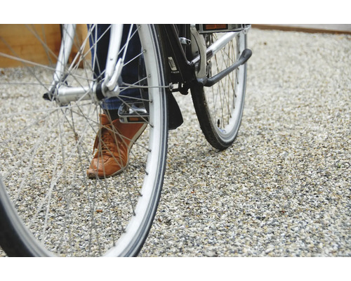 Prim-plan al unei biciclete cu o persoană pe un teren pietruit