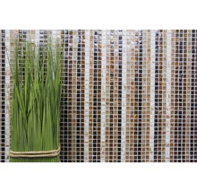 Plantă artificială decorativă verde în fața unui perete de mozaic din sticlă