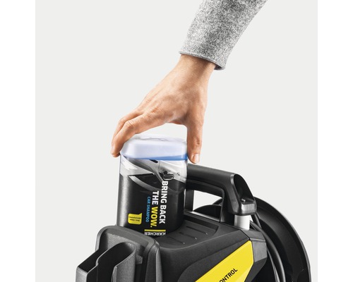 O mână așază o sticlă de șampon auto Kärcher pe un curățător cu presiune