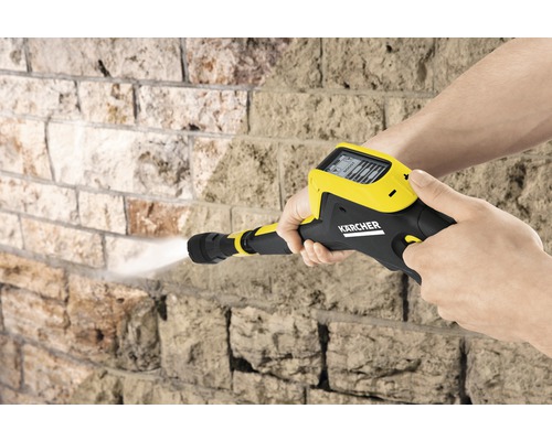 Aparat de curățat cu presiune Kärcher în uz pe un zid de piatră
