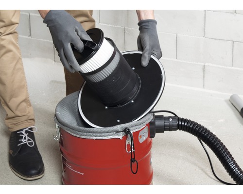 Un bărbat introduce un filtru într-un aspirator.