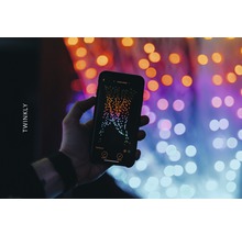 O mână ține un smartphone cu aplicația Twinkly în fața luminilor
