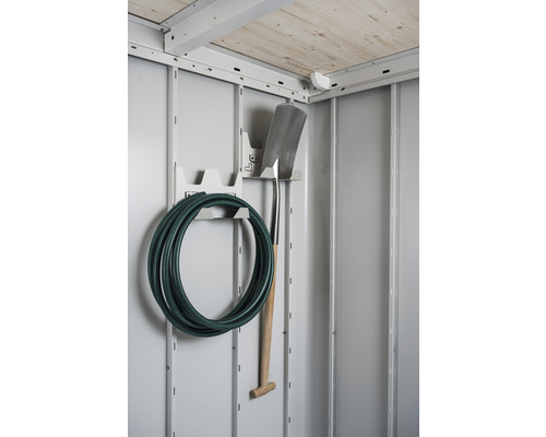 Interiorul unei magazii de grădină cu furtun de grădină și cazma pe suportul de perete