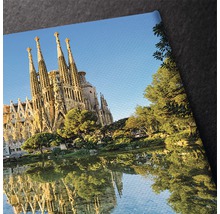 Prim-plan al unei imagini pe pânză cu Sagrada Familia și reflexia sa în apă