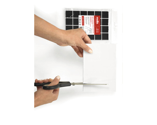 O persoană taie un suport de pâslă cu o foarfecă. Suporturile de pâslă pentru tăiere sunt vizibile în fundal.