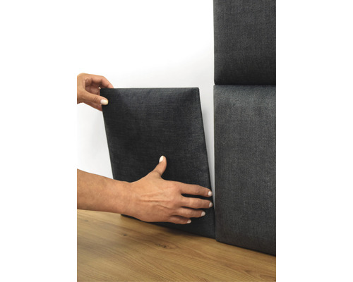 Persoană care fixează un panou acustic pe perete