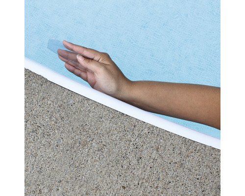 Mână atinge apa piscinei la marginea bazinului